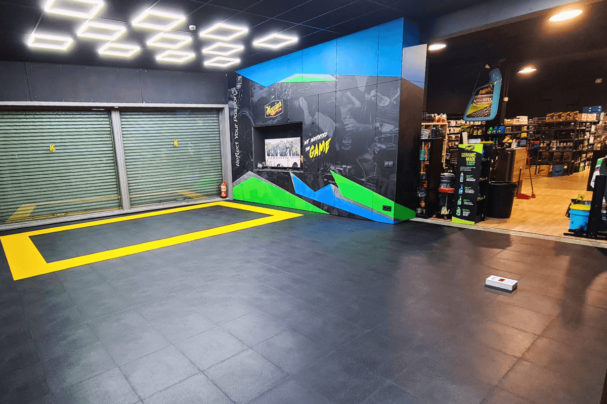 Dalles PVC Fortelock Invisible noires installées dans un hall de magasin spacieux et lumineux.