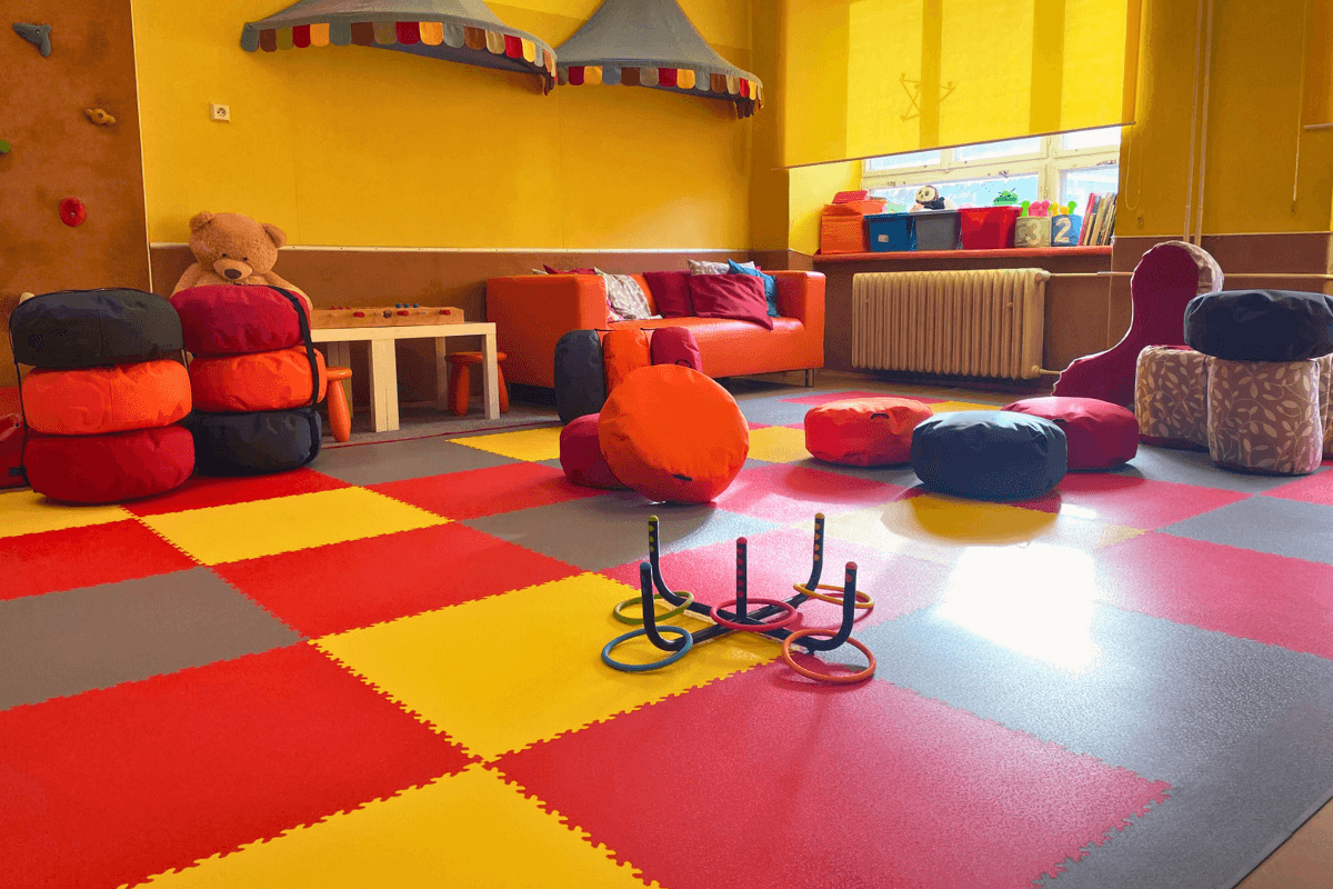 Dalles PVC Fortelock XL en graphite, jaune et rouge, créant un sol ludique et résistant dans une maternelle.