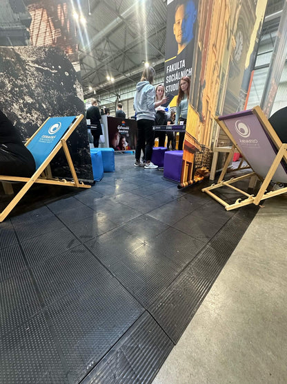 Dalles EVENT noires sur un stand d'exposition avec transats